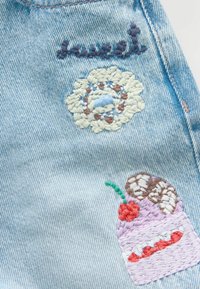 Jasnoniebieski denim ozdobiony kolorową haftowaną dekoracją: słowem "sweet", kwiatem oraz deserem z wiśnią i czekoladowymi akcentami.