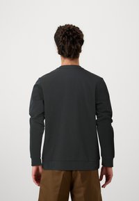 Hanorac lung cu mânecă lungă, de culoare gri închis, cu decolteu rotund și manșete dublate, confecționat dintr-un material moale. Design minimalist, fără modele evidente.