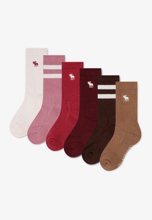Six paires de chaussettes côtelées en crème, rose à rayures, rouge, rouge foncé, marron à rayures et beige, chacune avec un petit logo élan près du haut.
