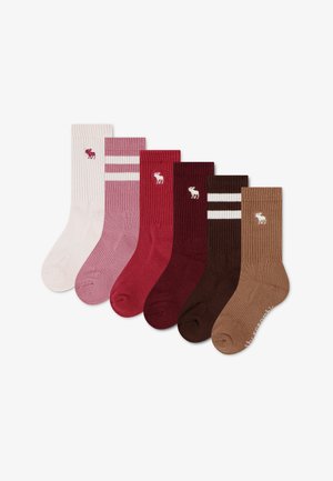 Six paires de chaussettes côtelées en crème, rose à rayures, rouge, rouge foncé, marron à rayures et beige, chacune avec un petit logo élan près du haut.