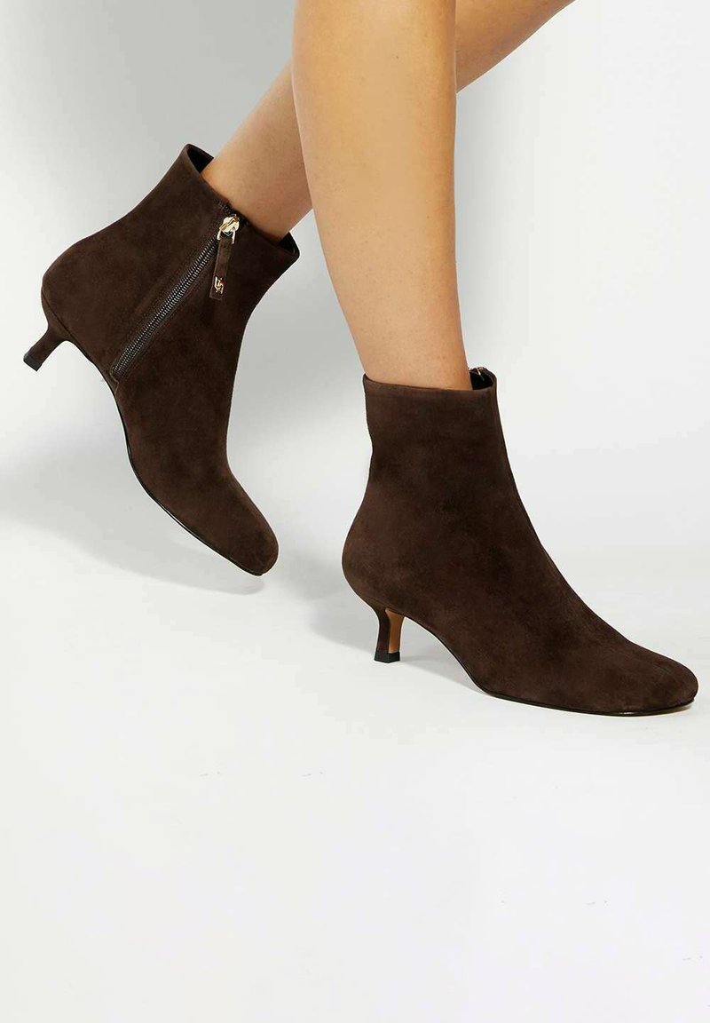 Bottines en suede marron avec un bout pointu et une fermeture éclair latérale décorative, présentant un talon étroit pour un soutien supplémentaire.