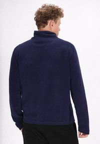 Pullover in pile blu navy con colletto rialzato e maniche lunghe, caratterizzato da una superficie liscia e un orlo dritto.