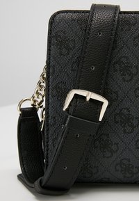 Sort textured taske med en kæde- og læderrem, rektangulær form, metal spænde hardware og subtil prægning.