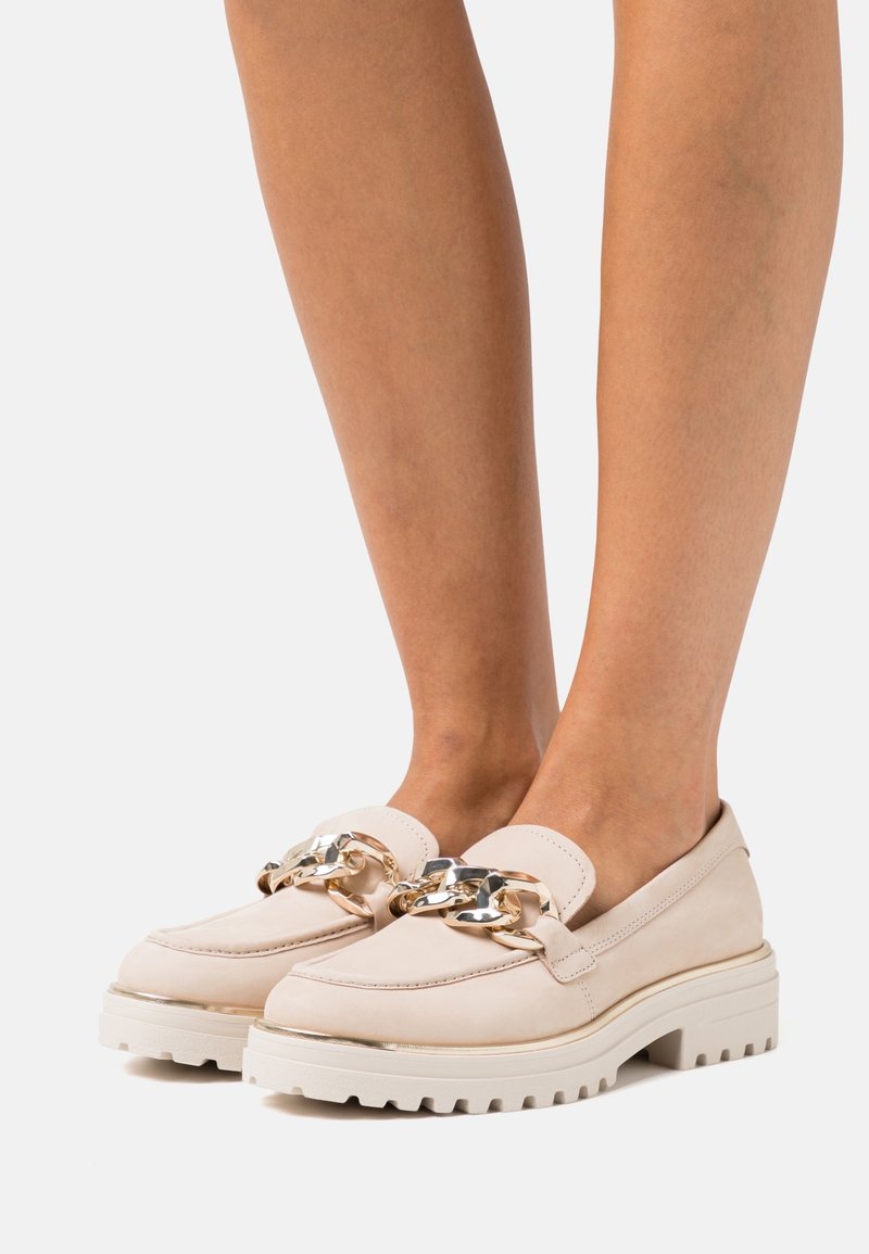 Ljust rosa loafers med en kraftig vit yttersula, prydd med en gyllene kedja över vinstocken och en slät mockasyta.