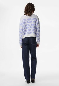 Stickad tröja i ljusgrå med ett lavendelfärgat blommönster, kombinerad med mörkblå raka jeans och svarta ankelboots.