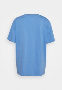 Kortärmad, löst sittande t-shirt i ljusblå bomull. Har en enkel rund halsringning och en subtil horisontell sömdetalj på baksidan.