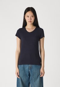 Σκούρο μπλε κοντομάνικο πουκάμισο V με λεπτό βαμβάκι, διακοσμημένο με μια μικρή λεπτομέρεια λογότυπου στο στήθος και εφαρμοστή σχεδίαση.