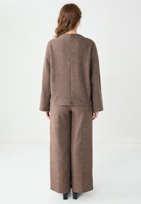 Top marrone lavorato a maglia e pantaloni a gamba larga realizzati in tessuto morbido e strutturato, caratterizzati da una vestibilità rilassata e da un semplice design con cucitura posteriore.