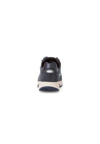 Chaussure de sport bleu foncé avec une tige lisse, semelle gris clair et détail de logo. Présente un bout arrondi et des accents texturés au niveau du talon.