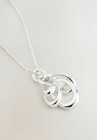 Zilveren hangersnoer met onderling verbonden ovale en ronde vormen met een gepolijste afwerking, opgehangen aan een delicate ketting.