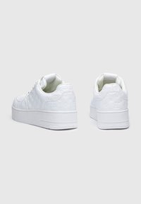Sneakers bianchi con piattaforma, dotati di una parte superiore testurizzata caratterizzata da modelli a logo impresso. Punta rotonda e colletto imbottito per il comfort. Suola in gomma.