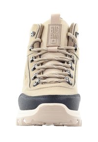 Beżowe buty trekkingowe z szarymi akcentami, posiadające wyraźne sznurowadła, metalowe oczka oraz teksturowaną gumową podeszwę. Logo na języku jako element identyfikacji marki.