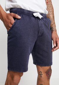 Pantalones cortos azul marino hechos de una tela suave, con una cinturilla elástica y cordón blanco, además de bolsillos laterales.
