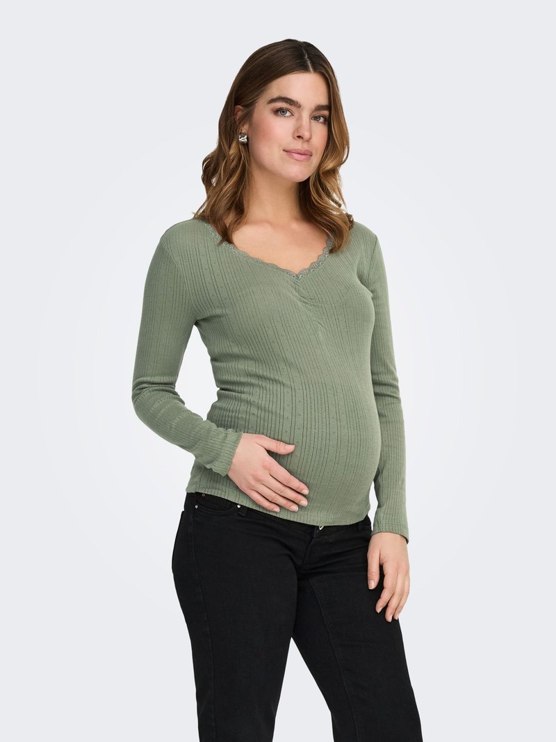 Barsel top i ribbet, blødt grønt stof med V-udskæring og bølget kant. Kombineret med sorte bukser, sidder tæt over maven.