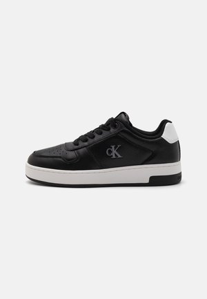 Sneaker in pelle nera con punta perforata, suola bianca e acento sul tallone bianco a contrasto. Presenta il logo di lato e lacci neri.