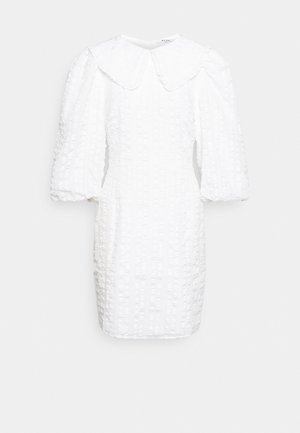 Vestido branco com um tecido texturizado, apresentando um grande colarinho arredondado e mangas bufantes. O design inclui riscas verticais.