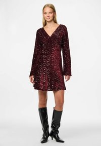 Burgundy paljetterklänning med lång ärm och V-ringning, lös passform, ovanför knäna längd, tillsammans med knähöga svarta glansiga stövlar.