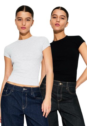 Dvě přiléhavá trička v šedé a černé barvě, kombinovaná s tmavě modrými džíny. Trička mají krátké rukávy a kulaté výstřihy.