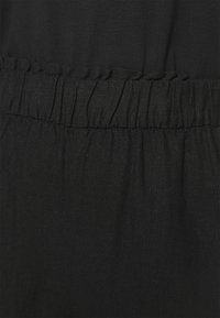 Tela negra con una superficie texturada, que presenta un detalle de cintura fruncida. Suave y ligeramente brillante, sin patrones visibles.