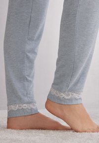Lichtblauwe pyjamabroek van zachte stof met kantafwerking aan de boorden. De boorden hebben een delicate golvende patroon.