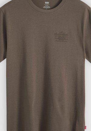 Braunes Levi's T-Shirt mit kurzen Ärmeln, kleinem, erhabenem Logo-Schriftzug auf der linken Brust und einem roten Levi's-Label an der unteren Seitennaht.