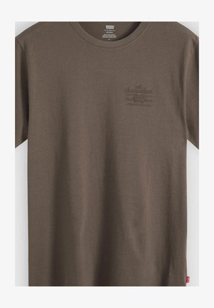 Braunes Levi's T-Shirt mit kurzen Ärmeln, kleinem, erhabenem Logo-Schriftzug auf der linken Brust und einem roten Levi's-Label an der unteren Seitennaht.
