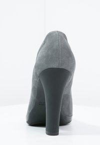 Chaussure à talon haut grise avec une texture en daim épurée, bout pointu et un talon noir robuste. Présente un design minimaliste sans ornements visibles.