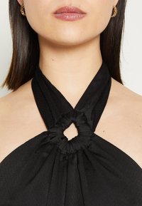 Top nero con scollo all'americana caratterizzato da un design torcigliante e un dettaglio centrale a nodo. Realizzato in tessuto testurizzato con una finitura liscia.