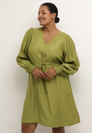 Un vestito verde con scollatura a V, maniche a palloncino e una vita smock. Il tessuto sembra liscio e leggero. Le rifiniture dell'orlo sono pulite.