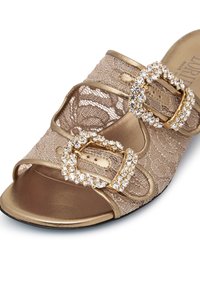 Gold slide sandal featuring lace upper, two ornate jewel-encrusted buckles, open toe, and a cushioned metallic gold insole.