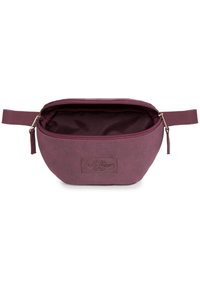 Bordeaux-kangasta valmistettu pussi, jossa on vetoketjusulku ja kohokuvioitu logo. Pyöreä muoto, jossa on sivukahva, sisävuori vastaa ulkopinnan väriä.