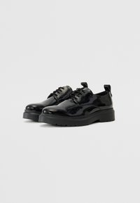 Chaussures en cuir verni noir au design élégant, à bout rond et semelle en caoutchouc épaisse. Comprend des lacets et des languettes à l'arrière.