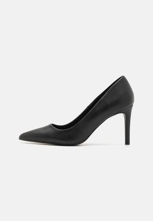 Pump nera con tacco alto e punta appuntita, realizzata in pelle liscia, caratterizzata da un design elegante e un tacco cilindrico sottile.