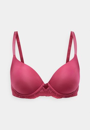 Soutien-gorge rembourré rose avec des coques lisses, une bande en dentelle et des bretelles satinées réglables. Il présente un petit nœud au centre et des détails en dentelle texturée.