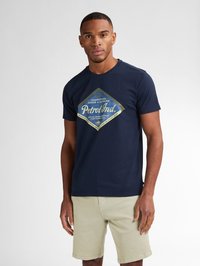 Námornická bavlněná tričko s diamantovým grafickým vzorem a žlutým a modrým textem. Design s kulatým výstřihem, krátké rukávy, doplněné s světlými šortkami.