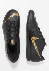 Schwarze Sportschuhe mit strukturiertem Obermaterial, goldenen Nike-Swoosh-Akzenten, Schnürdesign und einer gerippten Sohle für besseren Halt.