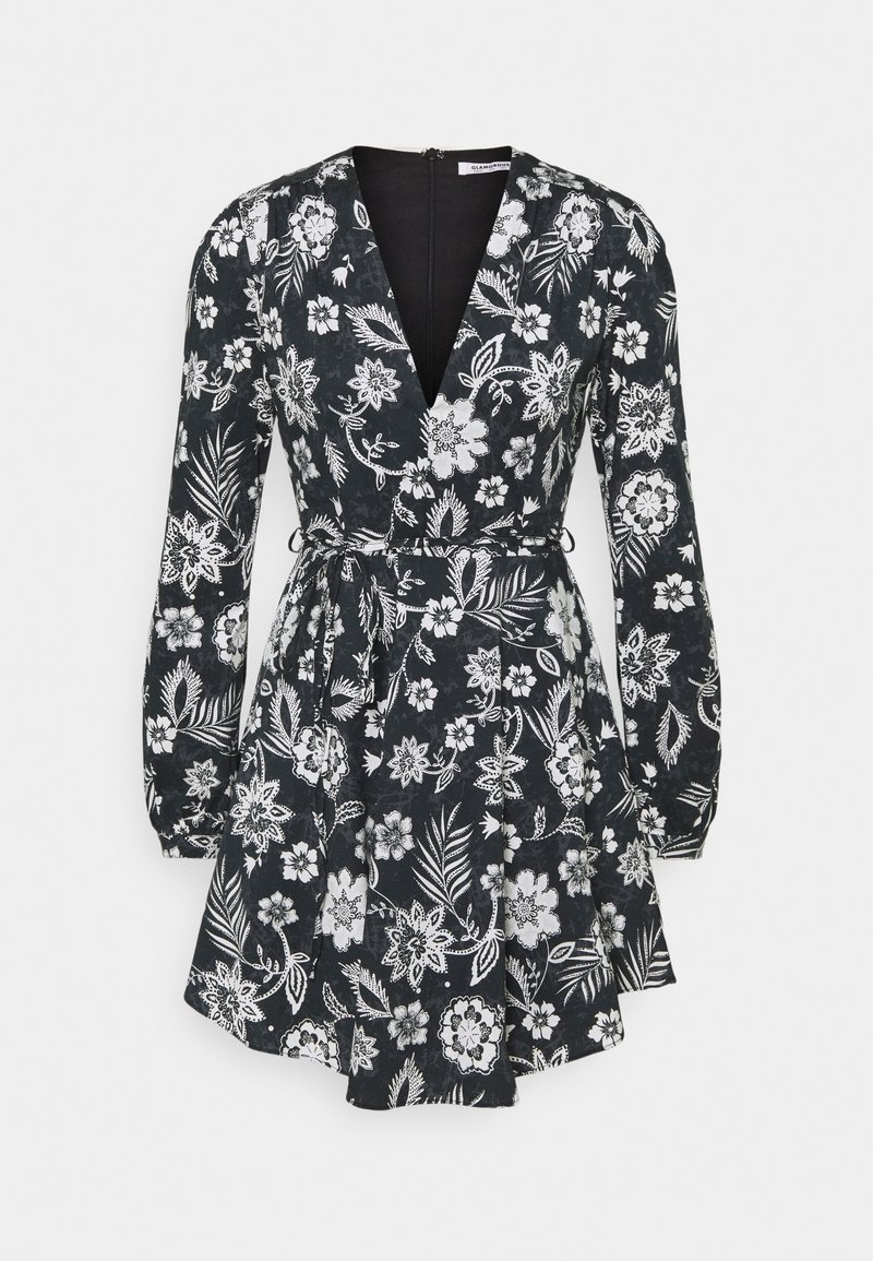 Robe noire à manches longues avec motif floral et feuilles blanches, encolure en V, taille cintrée avec ceinture à nouer et jupe évasée.