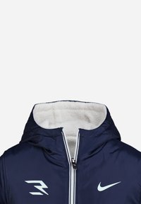 Doudoune bleu marine avec doublure en polaire blanche, fermeture éclair bidirectionnelle, capuche ajustable et logos sur la poitrine. Extérieur lisse et texture douce.