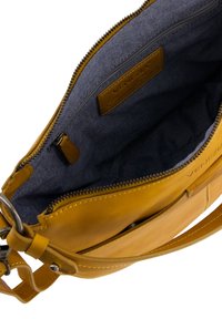 Gelbe Leder-Crossbody-Tasche mit glatter Oberfläche, Reißverschlussverschluss und einem mit Denim gefütterten Innenraum, der ein Markenlabel und eine zusätzliche Tasche enthält.