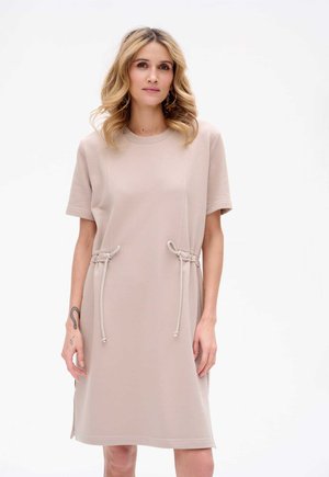 Beige jurk met korte mouwen en een ronde halslijn, met trekkoorddetails bij de taille en zijsplitten. Soepele textuur en een ontspannen pasvorm.