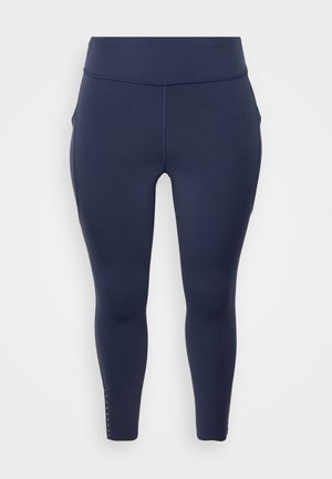 Marineblaue Leggings aus dehnbarem Stoff, mit hohem Taillenbund, seitlichen Taschen und dekorativen Nietenakzenten an den Knöcheln.