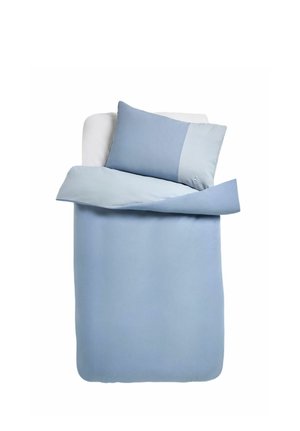 Einzelbett mit hellblauer und kariert blauem Bettbezug und passendem Kissen auf einem weißen Bettlaken vor weißem Hintergrund.