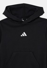 Hoodie noir en tissu doux avec une poche frontale. Le logo Adidas est brodé en argent sur la zone de la poitrine.