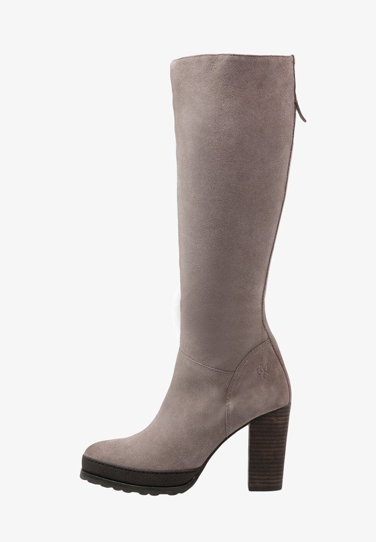 Knähöga stövlar i taupe mocka med hög staplad klack, rund tå, sidodragkedja och subtilt präglad logotyp nära klacken.
