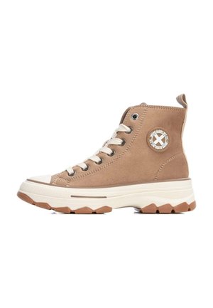 Zapatillas altas de ante color arena con la punta de goma blanca. Presentan cordones beige, ojetes plateados y una suela texturizada en crema y marrón.