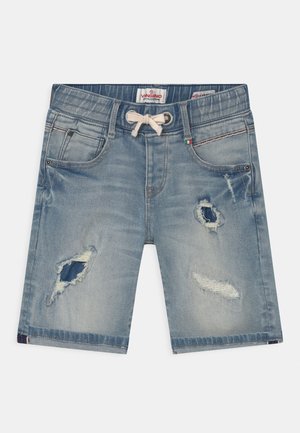 Pantalones cortos de mezclilla azul claro con cintura elástica, cordón, parches desgastados, bolsillos delanteros y una pequeña etiqueta con la bandera italiana en el lado derecho.