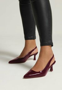 Décolleté in pelle verniciata bordeaux con punta affilata e tacco a blocco di altezza media, caratterizzati da un design elegante e apertura sulla schiena.