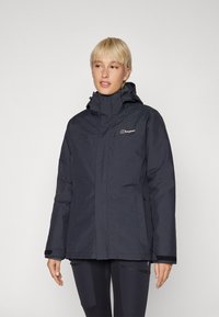 Navy waterproof jacket with a high collar, adjustable hood, and front pockets; features a zip and velcro closure for protection against elements.