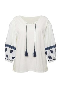 Blusa blanca con escote en V, bordado marino en las mangas abullonadas y borlas. Presenta un tejido texturizado y acentos de ribete marino en contraste.