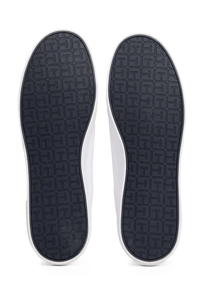 Zapatillas blancas con una suela texturizada en color marino que presenta un patrón geométrico. Los zapatos tienen un diseño suave y minimalista con un perfil bajo.